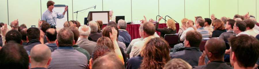 SafeStart Author and CEO Larry Wilson in front of a large workshop room rowded with people asking questions, the listeners raising hands in response